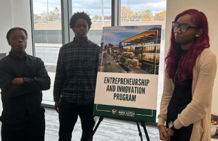  3 students standing next to the entrepreneurship program sign